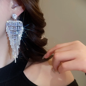 Close-up of sparkling silver tassel earrings with zircon flowers on a female model