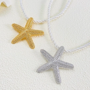 Detailed macro view of gold and silver starfish pendants with textured finish and white rope