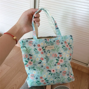 Detailed view of blue floral cotton handbag with daisy print and secure zipper closure
