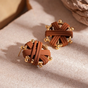 Close-up of vintage woven faux leather earrings with golden metal sphere accents