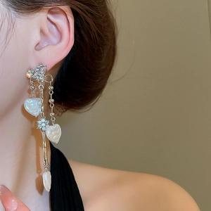 Détail de boucles d'oreilles pendantes avec nœud argenté et perles en cœur sur mannequin