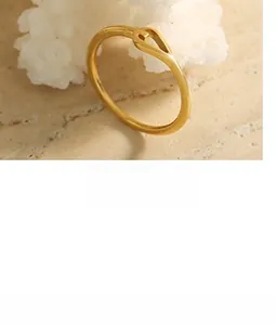 Détail d'une bague dorée minimaliste avec nœud torsadé sur une surface en marbre