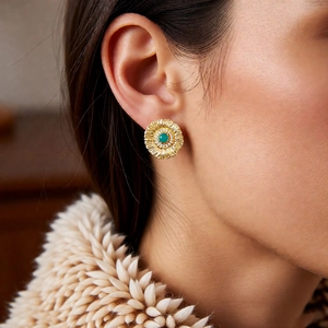 Close-up of vintage flower stud earring with green gemstone and diamond halo