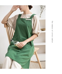 Detail of green cotton linen apron showing front pocket and minimalist shoulder straps