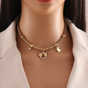 Close-up of golden woven necklace with butterfly ring pendant and rhinestone details