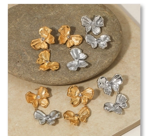 Detailed view of assorted bow earrings in gold and silver with zircon stones on stone