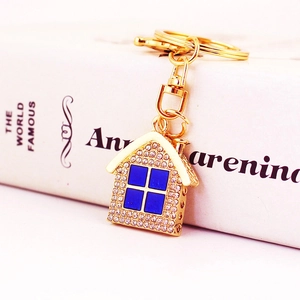 Colorful rhinestone house keychain with gold lobster clasp and ring on a book