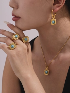 Nahaufnahme von vergoldetem Hammerschmuck-Set mit türkisfarbenen Anhängern und Ringen