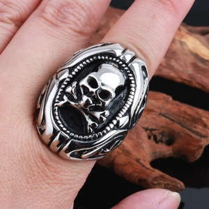 Vintage punk silver stainless steel skull ring for men worn on wooden background