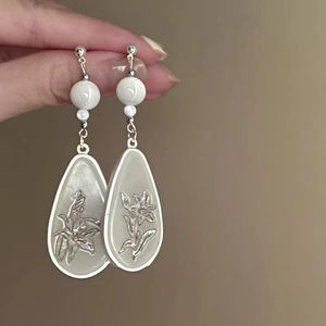 Close-up of silver flower tassel earrings with pearls held by hand for detail