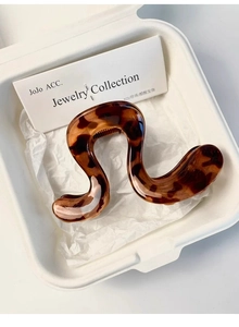 Macro view of leopard print wavy hair claw clip in a luxury gift box packaging