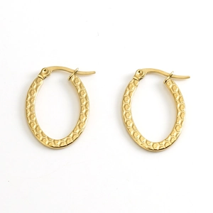 Macro detail of golden oval earrings featuring textured honeycomb pattern on steel surface