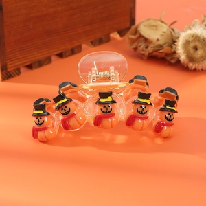 Close-up of Halloween pumpkin hair claw with orange figures and black wizard hats