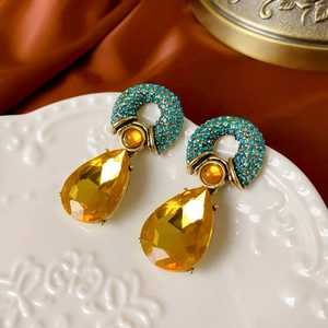 Detail of vintage gold earrings with turquoise rhinestones and amber crystal droplets
