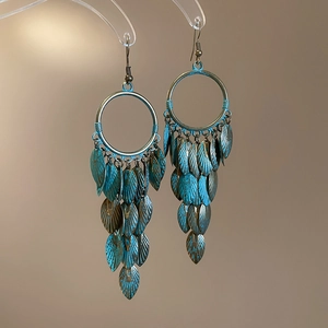 Detailed view of bohemian bronze leaf tassel earrings with vintage turquoise patina finish
