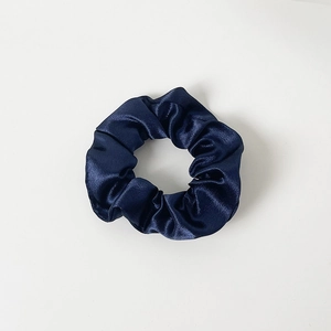 Detailed view of dark blue satin fabric texture on a high-shine hair scrunchie