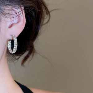 Close-up of a silver C-shaped star stud earring with sparkling crystals on a model's ear