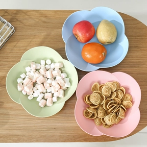Three flower-shaped snack plates in pastel blue, green, and pink on a wooden table
