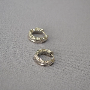Macro detail of silver lava textured earrings with irregular hammered metallic finish