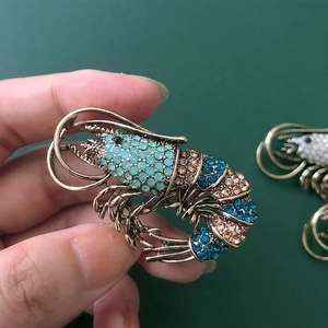 Detailed view of an ornate lobster brooch with vibrant turquoise and gold rhinestones