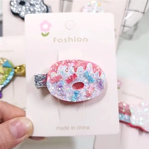 Pink glitter donut hair clip with colorful sprinkles on a white display card