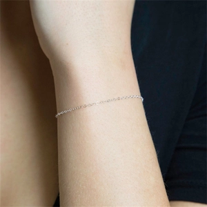 Detailed close-up of a minimalist silver stainless steel fine chain bracelet on a wrist