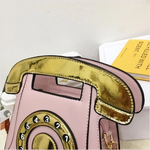 Close-up of pink vintage phone shaped crossbody bag with digital dial and metal D-ring