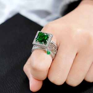 Luxury geometric silver ring with emerald-cut green gemstone and intricate镂空 band