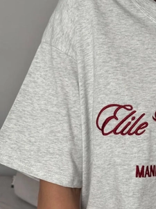 Détail de la broderie rouge Elite et texture en coton tricoté sur T-shirt gris