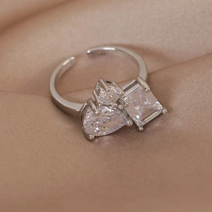 Detail of silver open ring with colorful zircon stones on golden silk fabric background