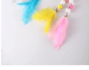 Detailed view of cat toy feathers, colorful fiber balls, and metal bells on white background