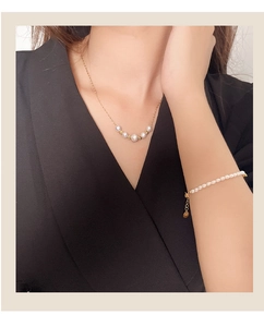 Detailed view of freshwater pearl necklace and bracelet set worn by a model in soft light