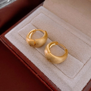 Gros plan de créoles en métal brossé doré placées dans un coffret cadeau à bijoux