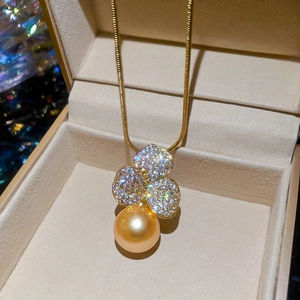 Close-up of gold flower pearl necklace with sparkling pavé stones in a jewelry box