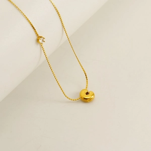 Close-up of golden puffy letter C pendant with sparkling zircon on a delicate chain
