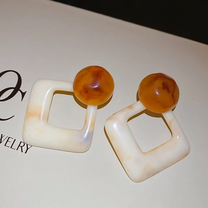 Close-up of vintage resin earrings with marble texture on a jewelry display card