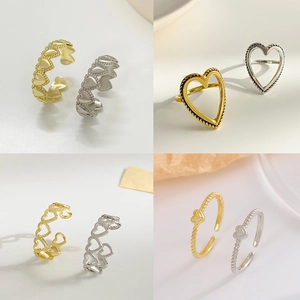Quattro stili di anelli a cuore aperti in oro e argento su uno sfondo minimalista