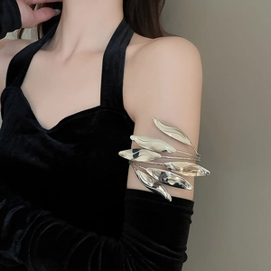 Detailed view of multilayer silver leaf arm cuff on model wearing a black velvet dress