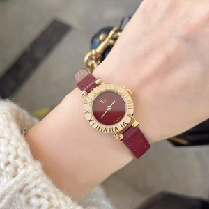 Close-up of a women's quartz watch with red leather strap and gold case on wrist