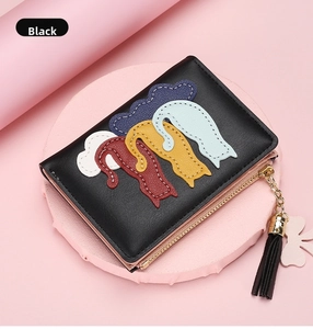 Close-up of black leather wallet with colorful cat patches and a pink flower tassel