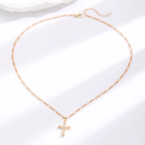 Detail of gold cross pendant necklace featuring cubic zirconia inlay and figaro chain