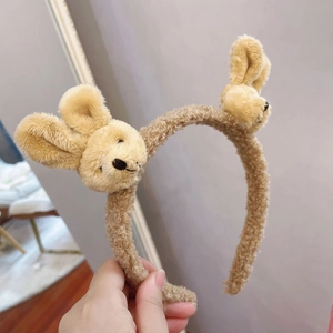 Detailed view of a soft brown plush bunny ear headband with cute embroidered features