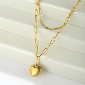 Detail of layered gold heart necklace featuring a thick paperclip chain and fine link