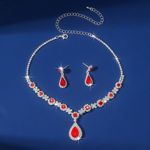 Macro shot of red teardrop crystal necklace and earrings set on dark blue background