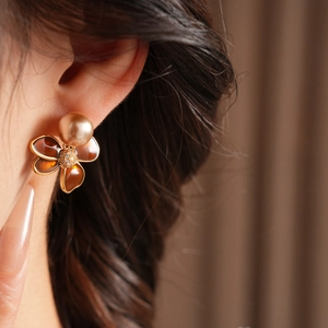 Gros plan de boucles d'oreilles vintage en fleurs dorées avec pétales ambrés et perles