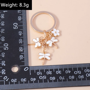 Detailed view of the cartoon dragonfly and flower keychain with a scale for size