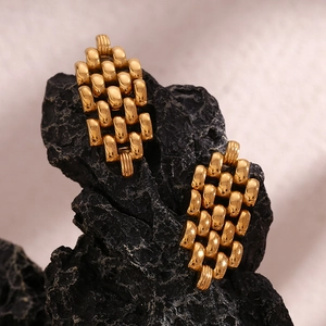 Detail of 18K gold plated chain link earrings on black stone, high-quality metal texture