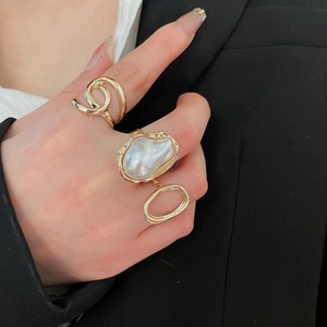 Close-up of golden textured band ring and baroque pearl ring on woman fingers