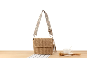 Detailed view of khaki hand-woven crossbody bag with geometric pattern strap and tassel