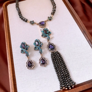 Macro detail of vintage teardrop pendant with purple stones and green rhinestones